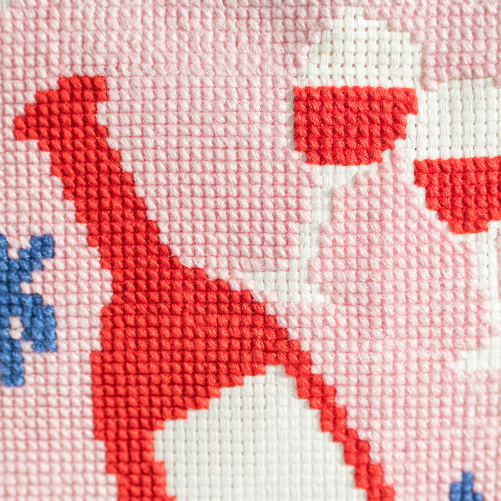 Wine bottle and glasses completed cross stitch piece on grey background 